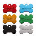 Six bone-shaped pet ID tags in red, blue, orange, green, black, and silver, arranged in two columns on a white background. The left column tags are engraved with the placeholder name 'NAME', while the right column tags are engraved with '085xxxxxxxx'.