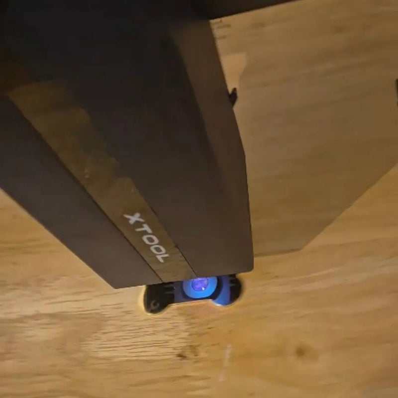 A close-up, angled view of a dark brown wooden furniture piece, likely a cabinet or shelf, with the brand name 'XTOOL' printed on the side, resting on a light-colored wooden floor.
